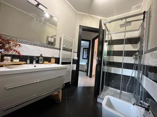 La salle de bains est pourvue d'un lavabo et d'une douche en verre. dans l'établissement Appartamento con giardino a 5 min dal Mare - Burlamacco House, à Viareggio