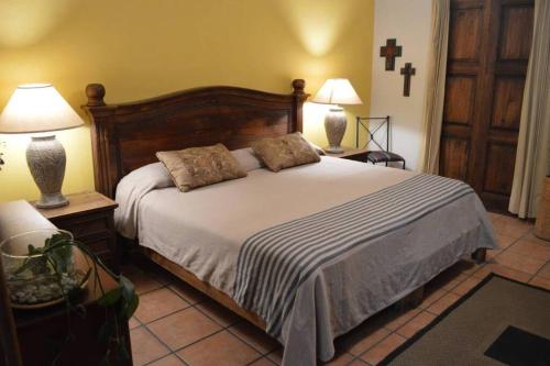 ein Schlafzimmer mit einem Bett mit zwei Lampen und einem Kreuz an der Wand in der Unterkunft en corazón centro Histórico, in Morelia