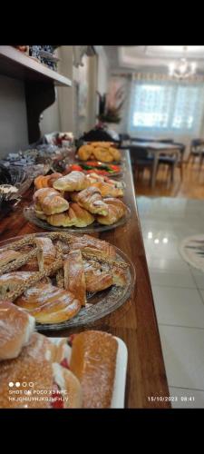 a table with several plates of bread and pastries at Vila Mariss in Korçë