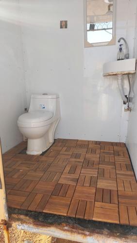 a bathroom with a toilet and a wooden floor at SandGlass Camp in Badīyah