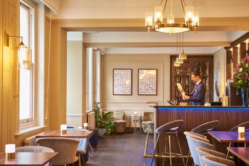 un homme debout au bar dans un restaurant dans l'établissement Phyllis Court Members Club, à Henley-on-Thames