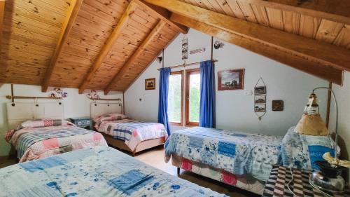 a bedroom with three beds in a room with wooden ceilings at CABAÑAS LOS ARÁNDANOS in Tolhuin