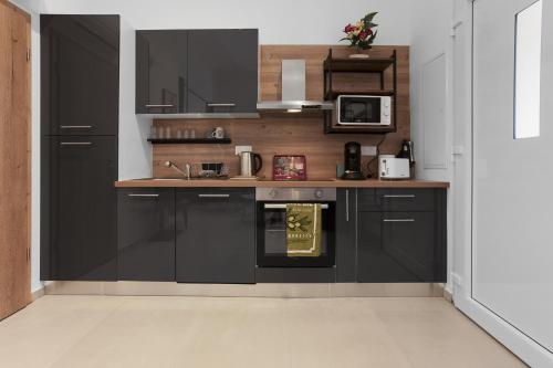 - une cuisine avec des armoires noires et une cuisinière dans l'établissement Appartement Moderne 1 à Fréjus, à Fréjus