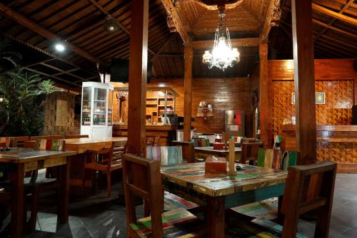 un restaurante con mesas y sillas de madera y una lámpara de araña en North Wing Canggu Resort en Dalung