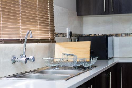 a kitchen sink with a dish basket on the counter at Waterford Executive Apartments in Mbabane