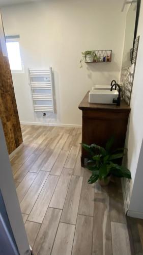 a room with a wooden floor with a sink and a fan at Maison de charme 3 chambres in Saligny-sur-Roudon