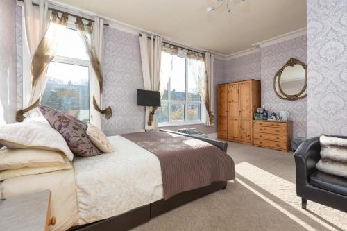 a bedroom with a bed and a chair and a mirror at The Fairmile in Lytham St Annes