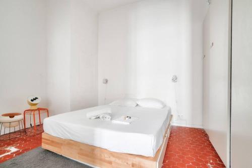- une chambre avec un lit blanc et un sol rouge dans l'établissement Splendide T2 avec balcon à 10 min du Vieux Port, à Marseille
