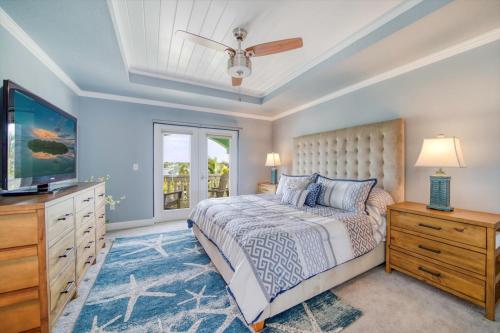 a bedroom with a bed and a flat screen tv at Waterfront Luxury w/ Heated Salt Pool & Golf Cart in Clearwater Beach