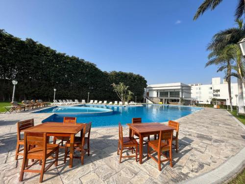 2 mesas y sillas frente a una piscina en Hotel Hacienda Lima Norte, en Lima