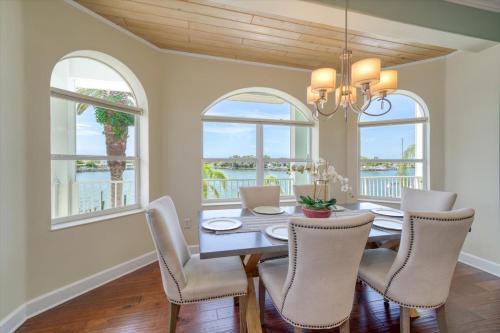 a dining room with a table and chairs and windows at Waterfront Luxury w/ Heated Salt Pool & Golf Cart in Clearwater Beach