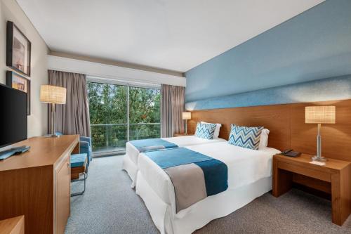 a hotel room with a large bed and a desk at Hotel Do Caracol in Angra do Heroísmo