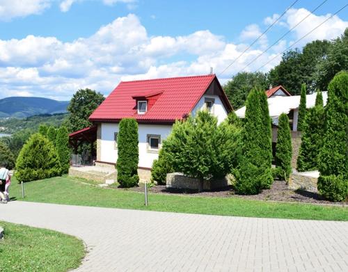 a white house with a red roof and some bushes at Apartmánový dom v Panoráma Parku in Nezbudská Lúčka
