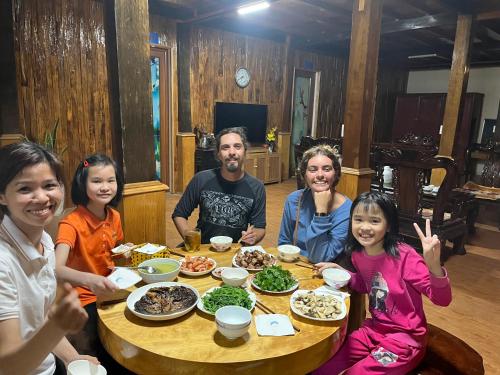 a group of people sitting around a table with food at Homestay Hoà Thảo in Mù Cang Chải