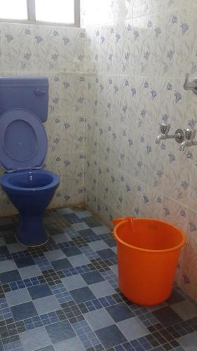 baño con aseo azul y cubo de naranja en Happy Tourist Home Neyyardam, en Parattipalli