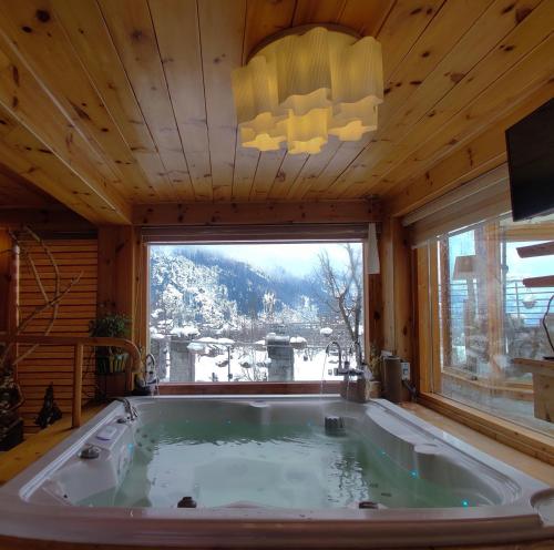 a large bath tub in a room with a large window at Chalet Shanag Manali in Manāli