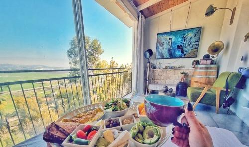 uma mesa com um prato de comida e uma janela em על קצה ההר em Yoqne‘am