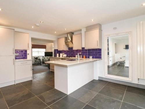a kitchen with white cabinets and purple tiles at Beautiful Holiday Home Village Sleeps up to 6 in West Hallam