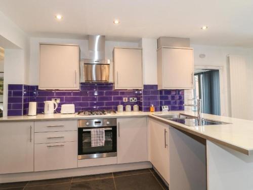 una cocina con armarios blancos y baldosas moradas en Beautiful Holiday Home Village Sleeps up to 6, en West Hallam