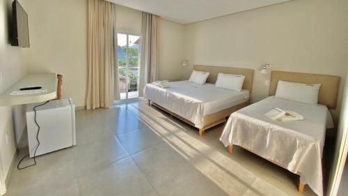 a bedroom with two beds and a television in it at Pousada Aquino Mar in Paraty