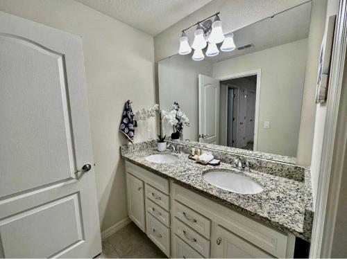 La salle de bains est pourvue de 2 lavabos et d'un grand miroir. dans l'établissement Orlando Relax, à Davenport