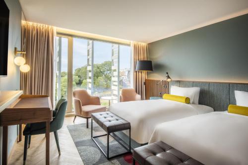 a hotel room with two beds and a desk at Renaissance Porto Lapa Hotel in Porto