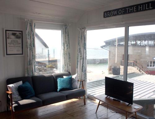 a living room with a couch and a flat screen tv at The Little Beach House, Sennen Cove in Sennen