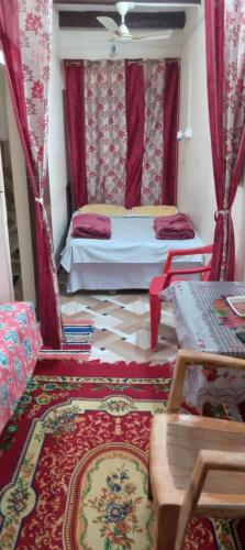 バラナシにあるKALYANI HOME STAY IN VARANASIのベッドルーム1室(赤いカーテンとラグ付きのベッド1台付)
