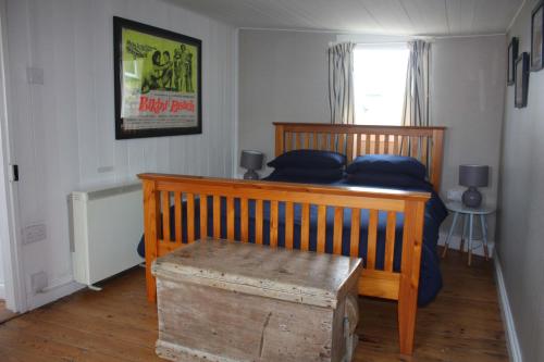 a bedroom with a wooden bed with blue pillows at The Little Beach House, Sennen Cove in Sennen