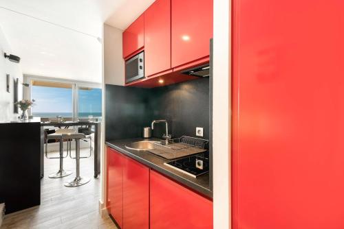 une cuisine avec des armoires rouges et un comptoir noir dans l'établissement Biarritz - Residence Victoria surf - Face océan, à Biarritz