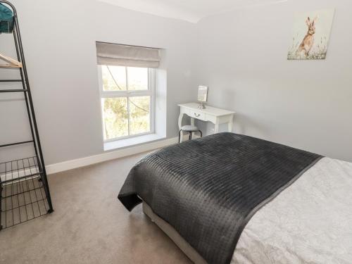 a bedroom with a bed and a desk and a window at Golygfa Bryn in Porth