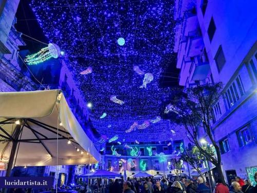 a crowd of people standing in front of a building with blue lights at Contrada Cafaro in Salerno