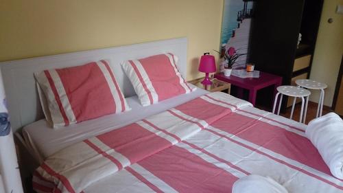 a large bed with pink and white sheets and pillows at Apartments Kamenecki in Krapina