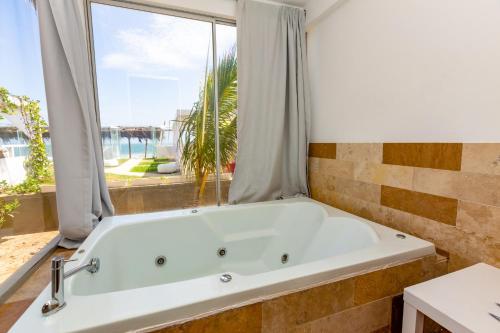 a bath tub in a bathroom with a large window at Hotel Del Mar Mancora in Máncora