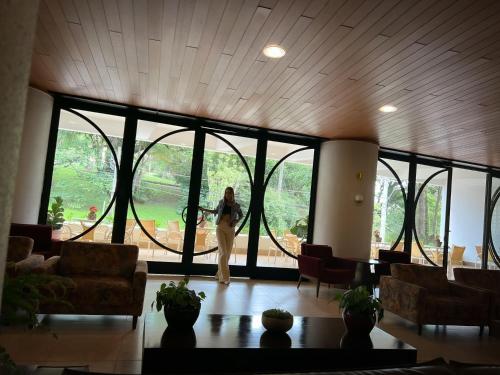 a woman standing in a room with a large window at Panorama Hotel in Águas de Lindóia