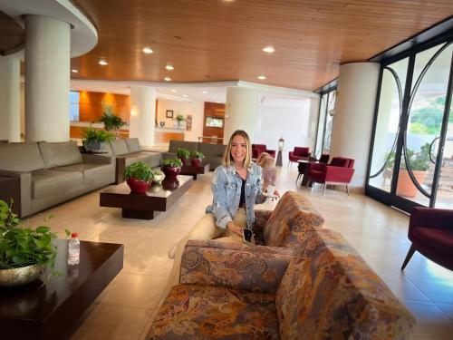 a woman sitting on a couch in a living room at Panorama Hotel in Águas de Lindóia