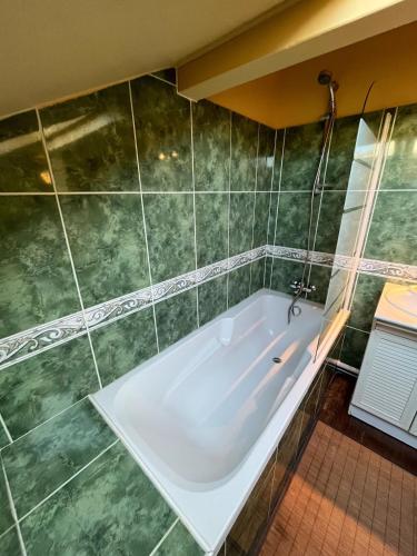 La salle de bains est pourvue d'une baignoire et de carrelage vert. dans l'établissement Biarritz Beaurivage - Proche Cote des Basques, à Biarritz