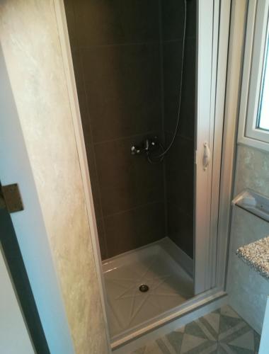 une douche avec une porte vitrée dans une salle de bain dans l'établissement Bungalow tout confort avec accès direct à la plage, à Gruissan