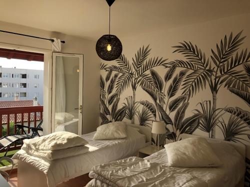 une chambre avec deux lits et une fresque de palmiers dans l'établissement Biarritz - Petricot - Balcon - Calme, à Biarritz