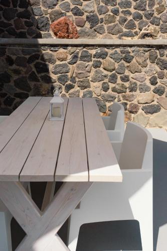 a wooden picnic table in front of a stone wall at Villas Scirocco in Fira
