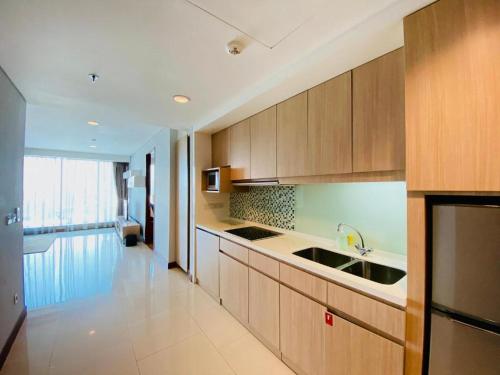 a kitchen with wooden cabinets and a sink at The H Tower Rasuna Suites Kuningan Jakarta By Villaloka in Jakarta
