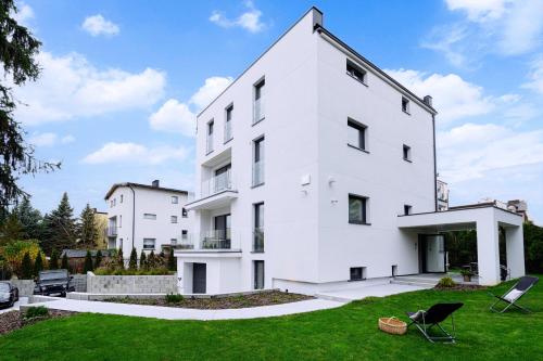 a white building with a lawn in front of it at LUBLIN RESIDENCE Butikowe apartamenty, zamknięty parking, ogród, 2x klimatyzacja, ekspres z młynkiem, prywatne wejście in Lublin