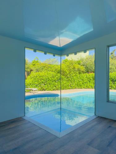 an empty house with a swimming pool viewed through a window at Rancho Litoral Búzios in Búzios