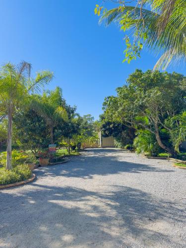 a gravel driveway with trees and a blue sky at Rancho Litoral Búzios in Búzios