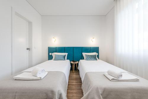 two beds in a room with white and blue at Hotel Grande Rio in Porto
