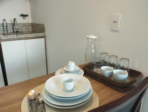 un tavolo con piatti e tazze sopra di Terra Hospedagem Apartamento luxuoso Soho a Campos dos Goytacazes