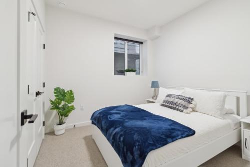 ein weißes Schlafzimmer mit einer blauen Decke auf einem Bett in der Unterkunft Luxurious & Stylish 2BR P/Suite, Near Vancouver in Langley