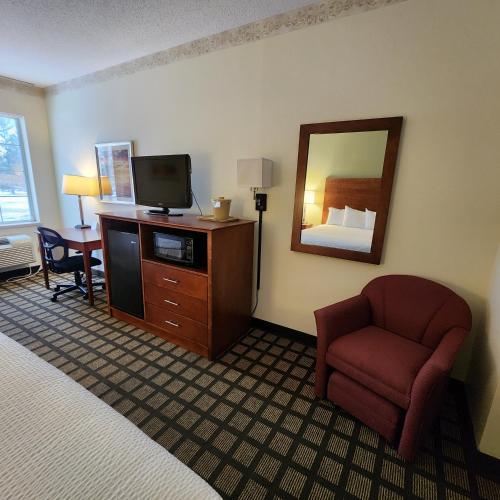 a hotel room with a bed and a tv and a chair at Baymont by Wyndham Mackinaw City in Mackinaw City
