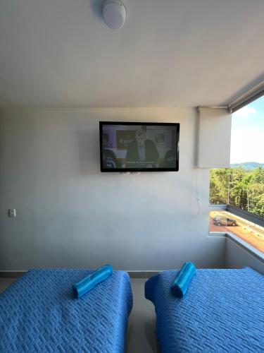 a bedroom with two beds and a tv on the wall at Apto de lujo. Ricaurte-Girardot in Ricaurte