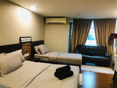 a hotel room with two beds and a couch at FirIzzkey Studio in Kota Bharu